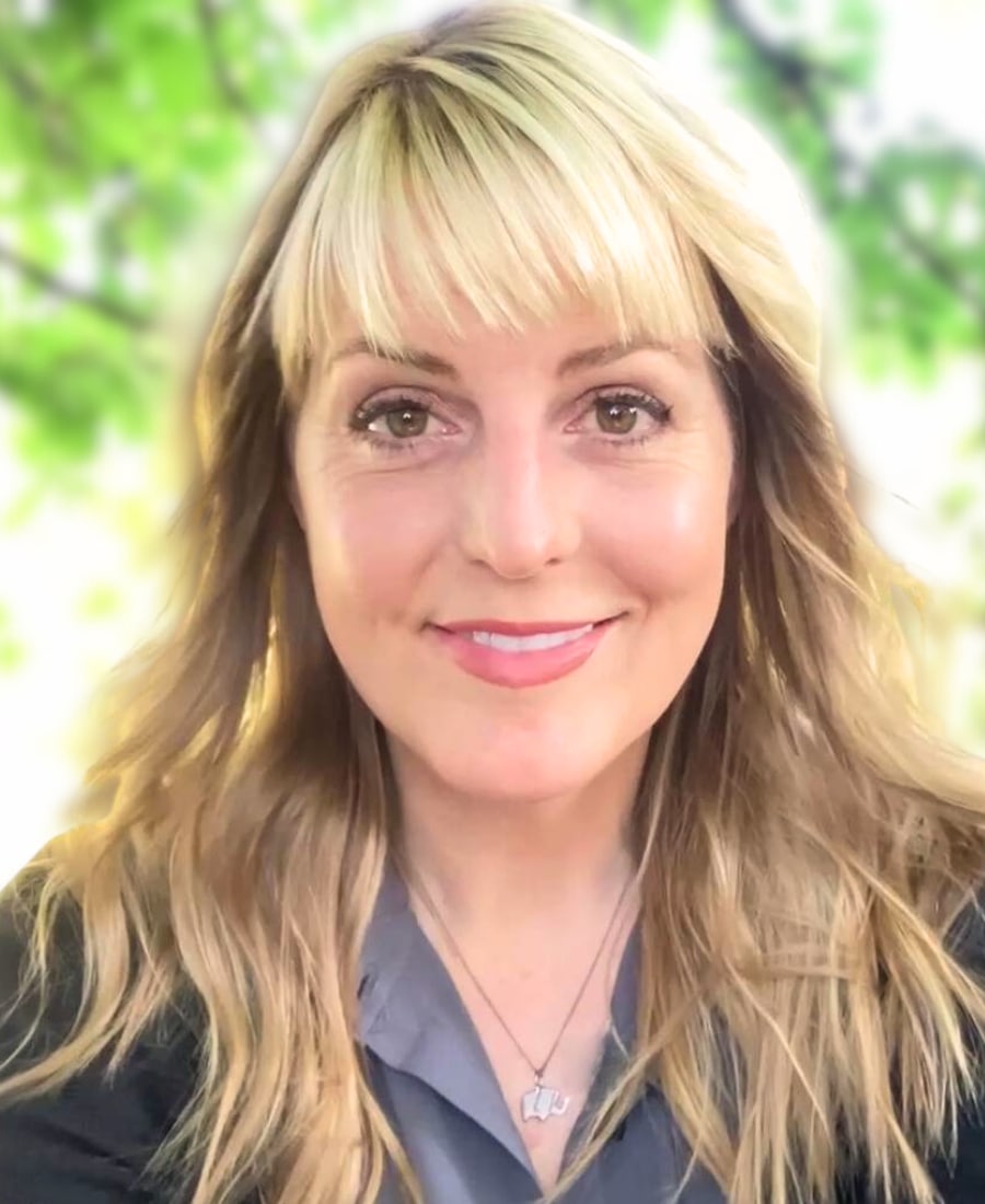 Headshot of Debbie Ethell, elephant conservation scientist and author, smiling outdoors with green leafy background.