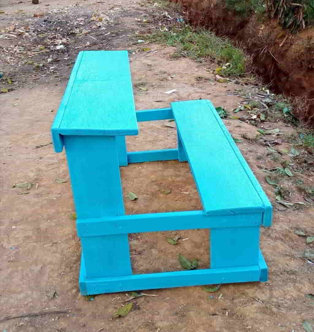 Bright blue wooden school desk sitting outdoors on the ground.