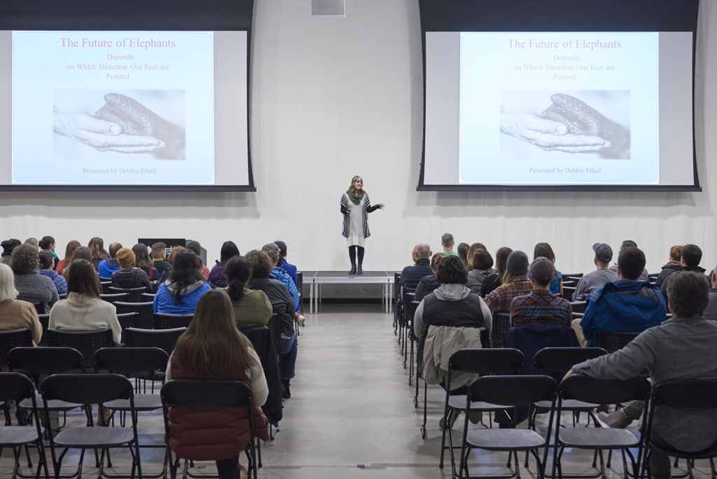 Debbie Ethell elephant conservation scientist and author onstage giving a presentation at the headquarters of Columbia Sportswear in front of a large live audience.